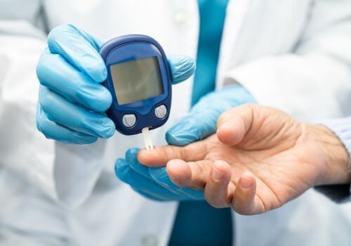 Healthcare worker checking blood sugar with a glucometer on a patient’s finger