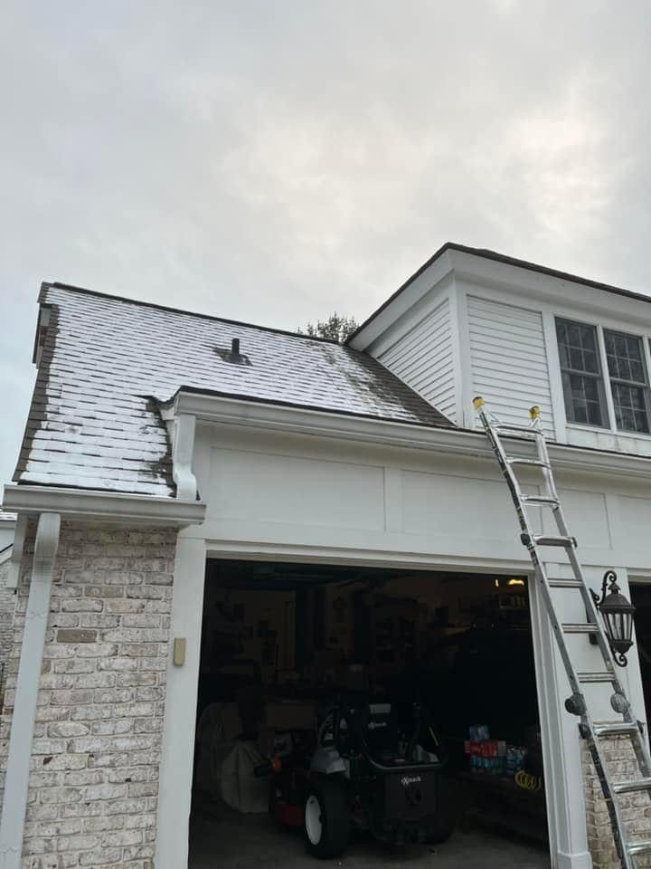 A ladder is sitting on the roof of a house next to a garage.