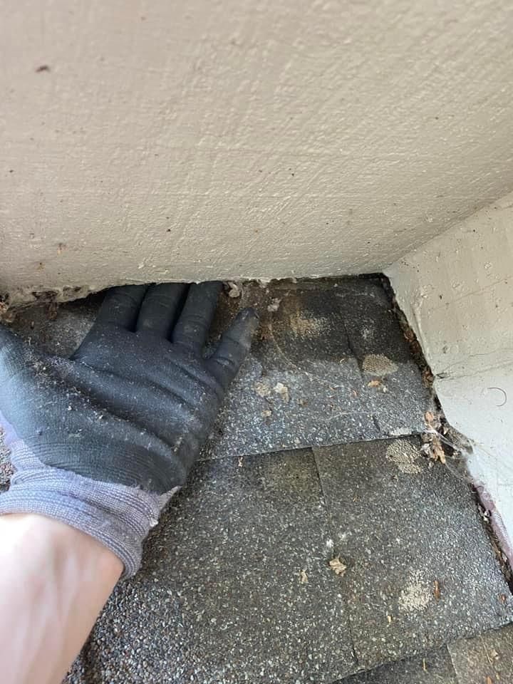 A person wearing gloves is looking under a roof.
