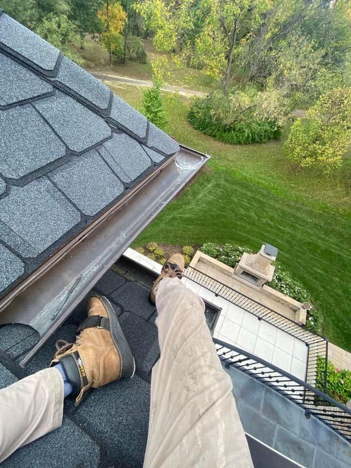 A person is laying on the roof of a house.