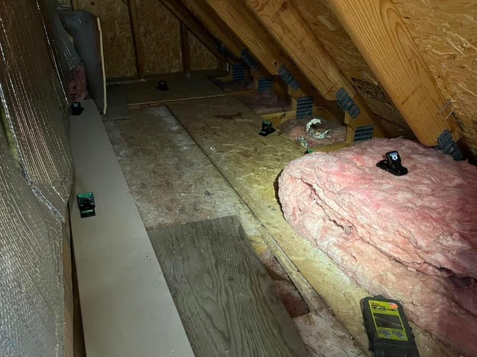 An attic with insulation and a level on the floor.