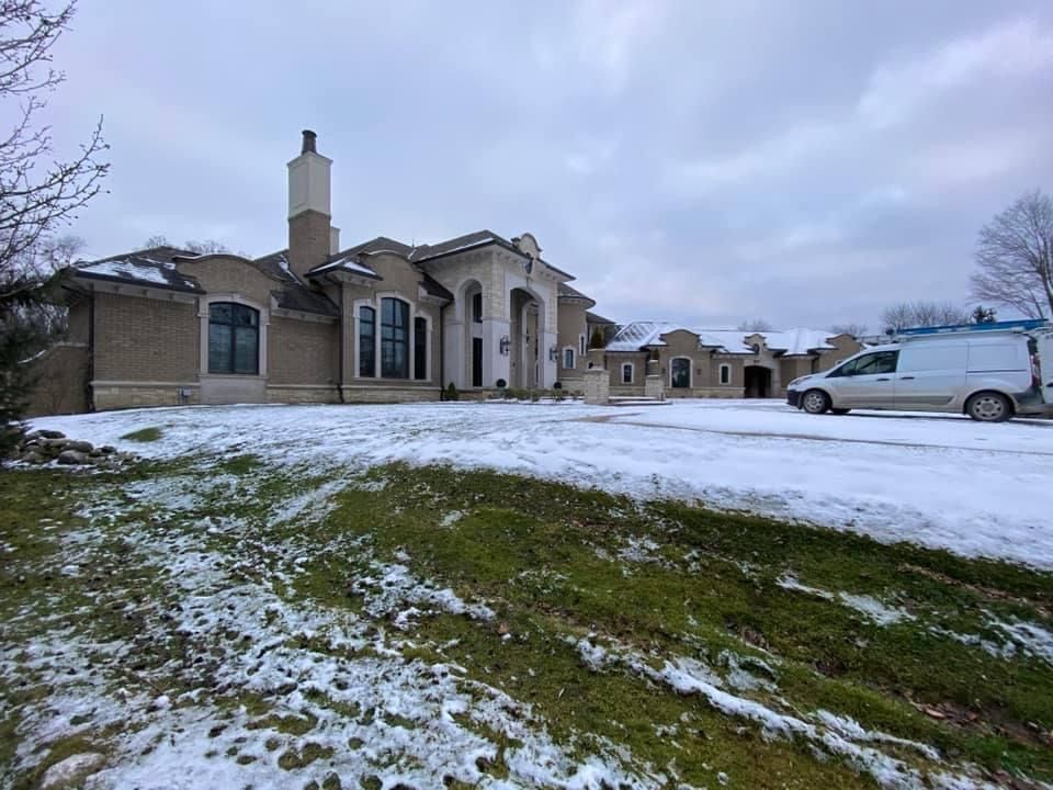 A large house with a van parked in front of it in the snow.