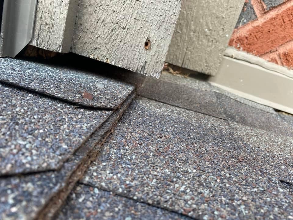 A close up of a roof with a brick wall in the background.