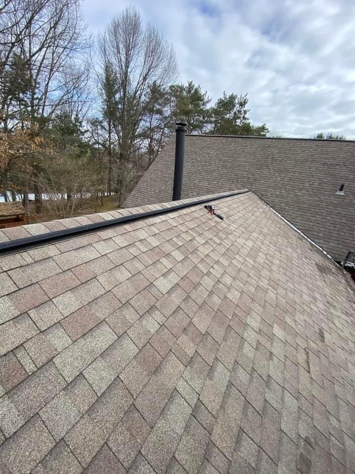 A roof with a chimney on top of it and trees in the background.
