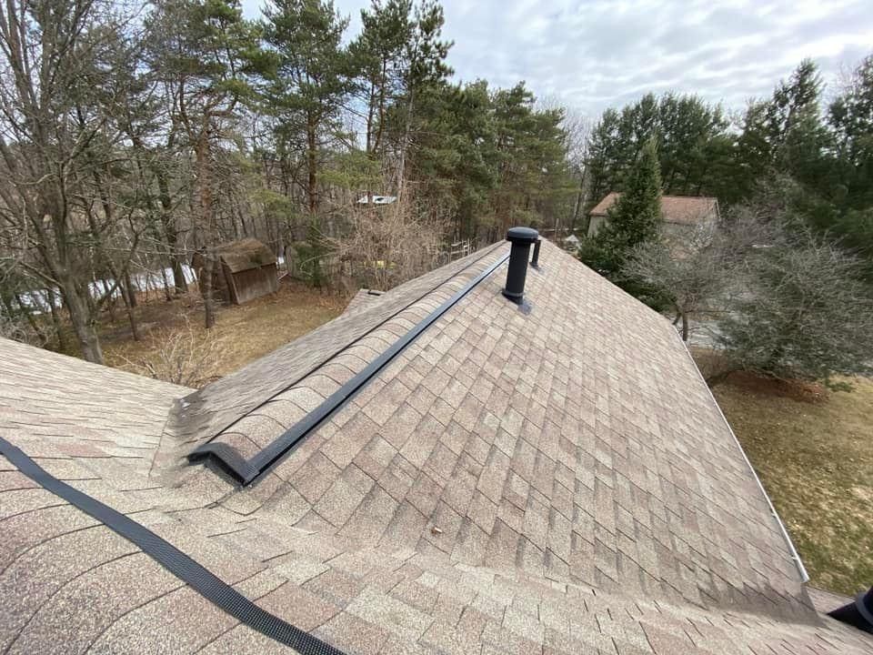 A roof with a chimney on it and trees in the background.