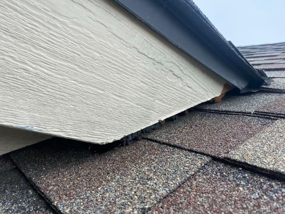 A close up of a roof with shingles and a roof gutter.