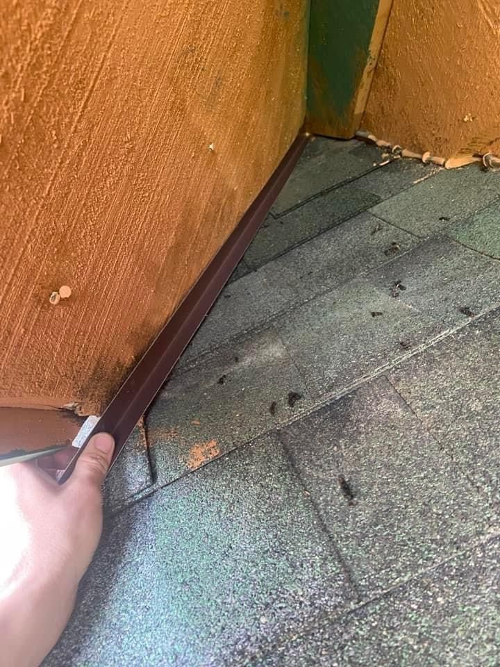 A person is holding a piece of wood next to a wall.