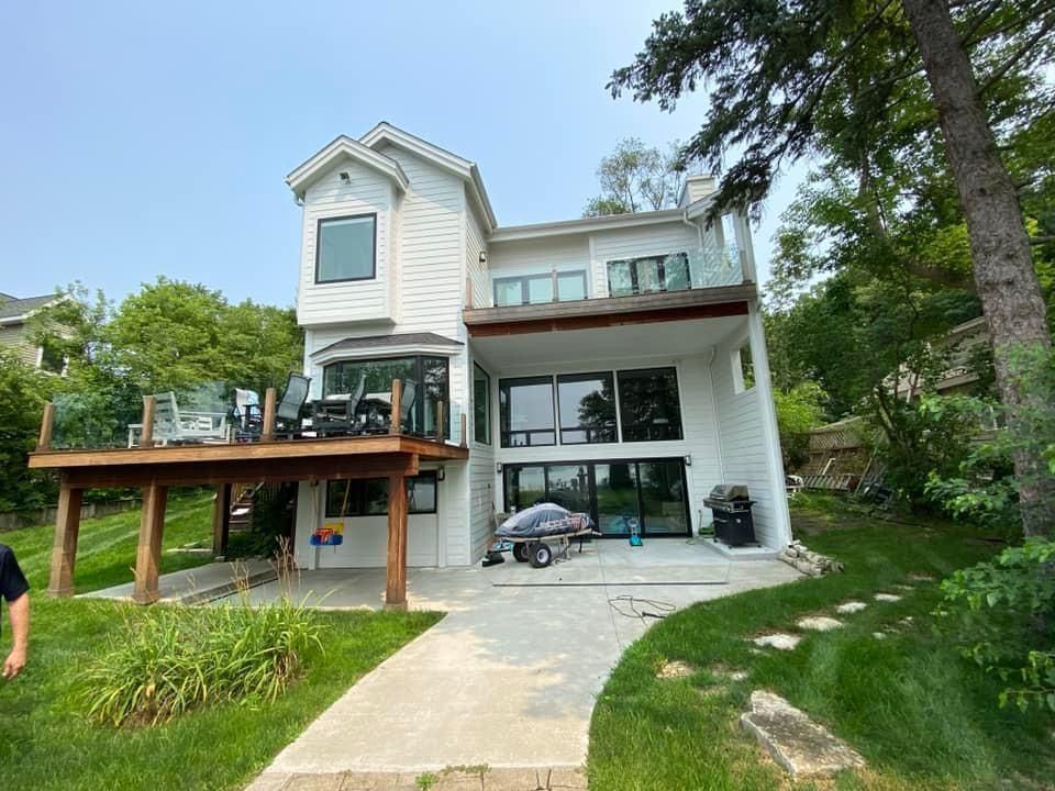 A large white house with a large deck and a car parked in front of it.