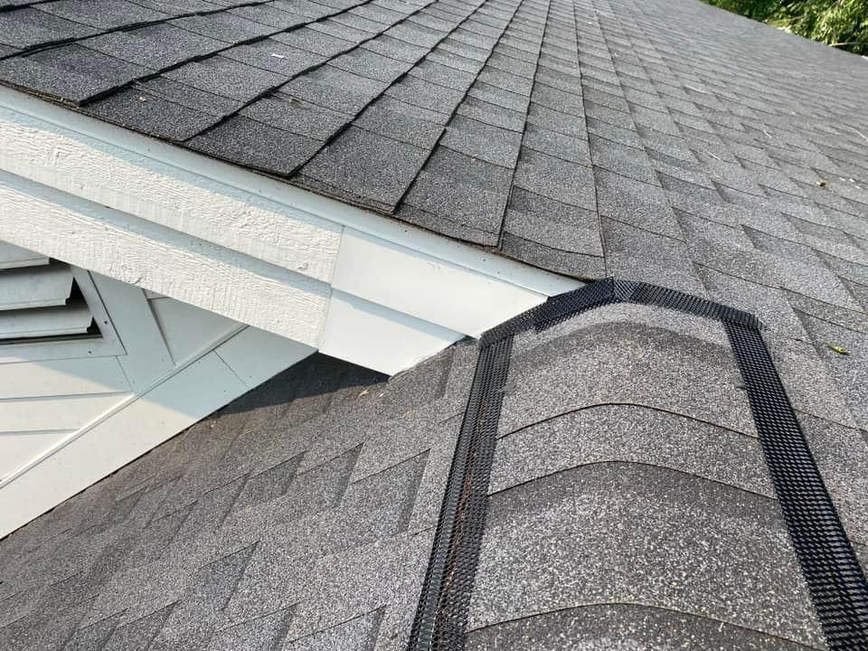 A close up of a roof with shingles and a gutter.