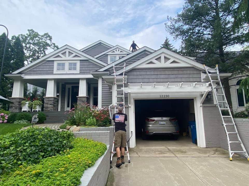 A man is standing on a ladder in front of a house.