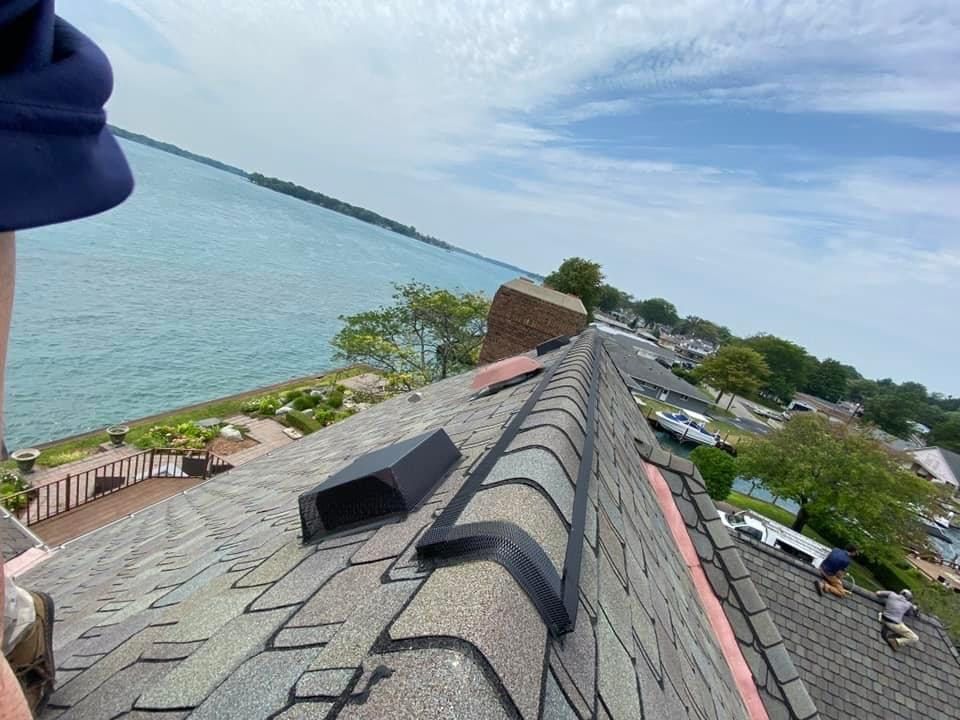A person is standing on top of a roof overlooking the ocean.