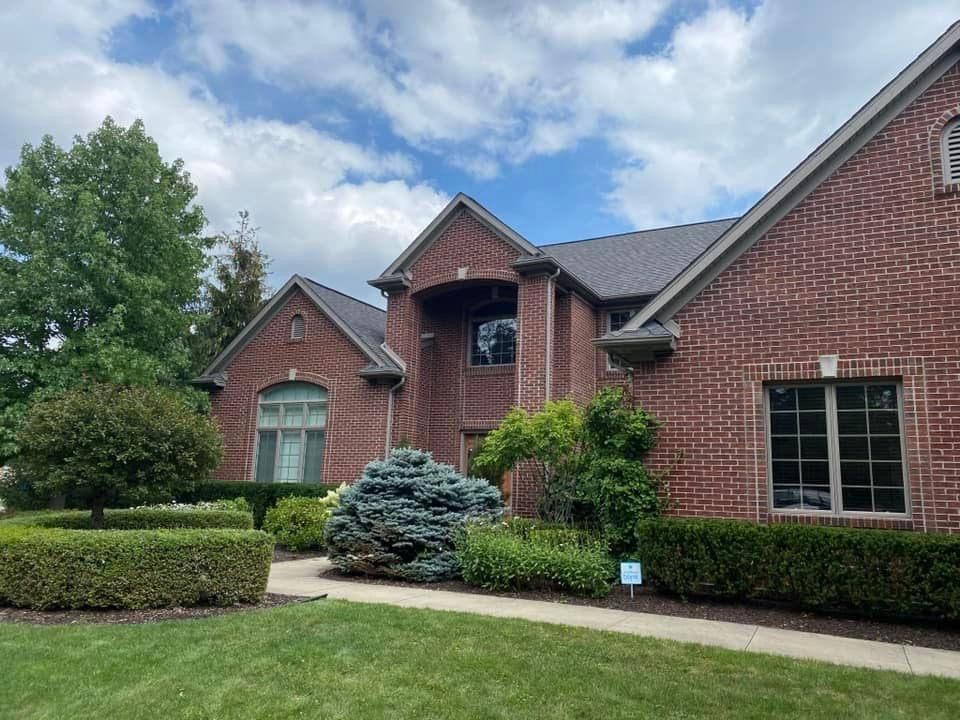 A large brick house with a lush green lawn in front of it.