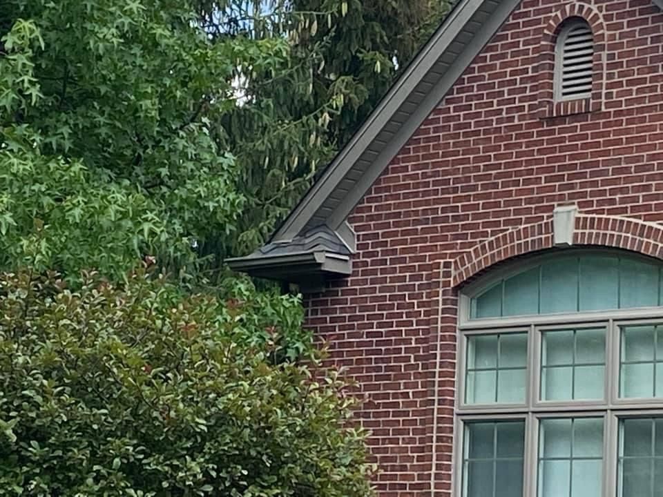 A brick house with a large window and trees in the background.