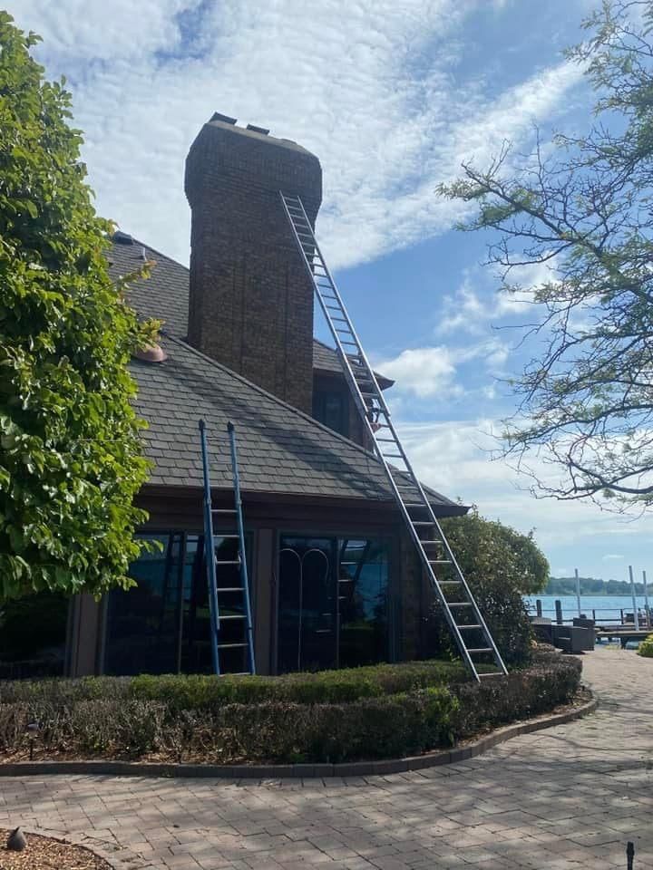 A ladder is sitting on the side of a house next to a chimney.