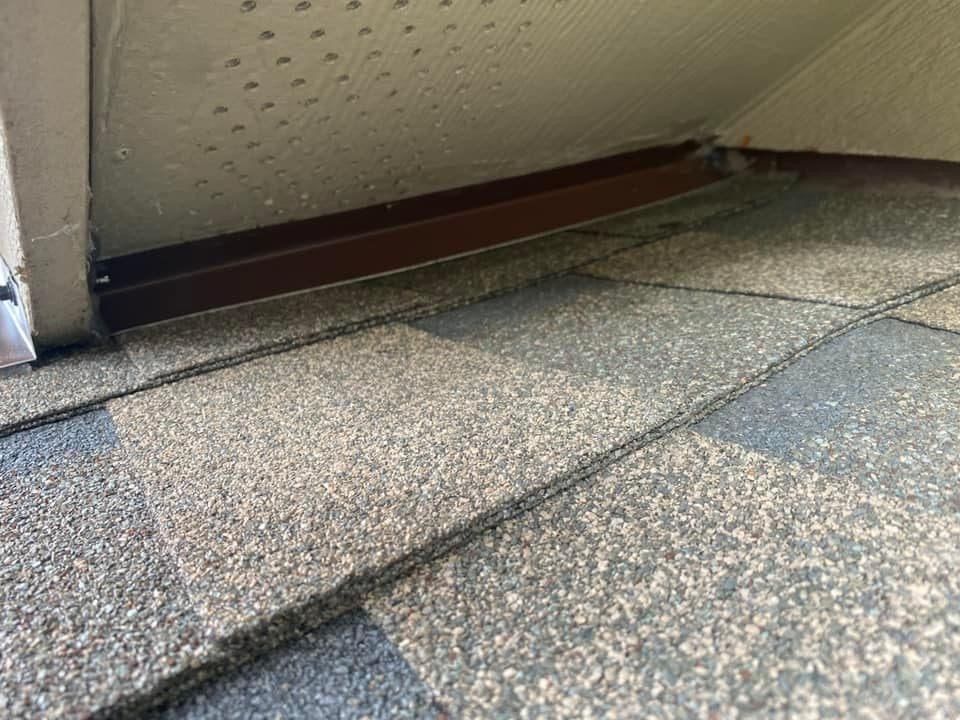 A close up of a roof with a door in the background.