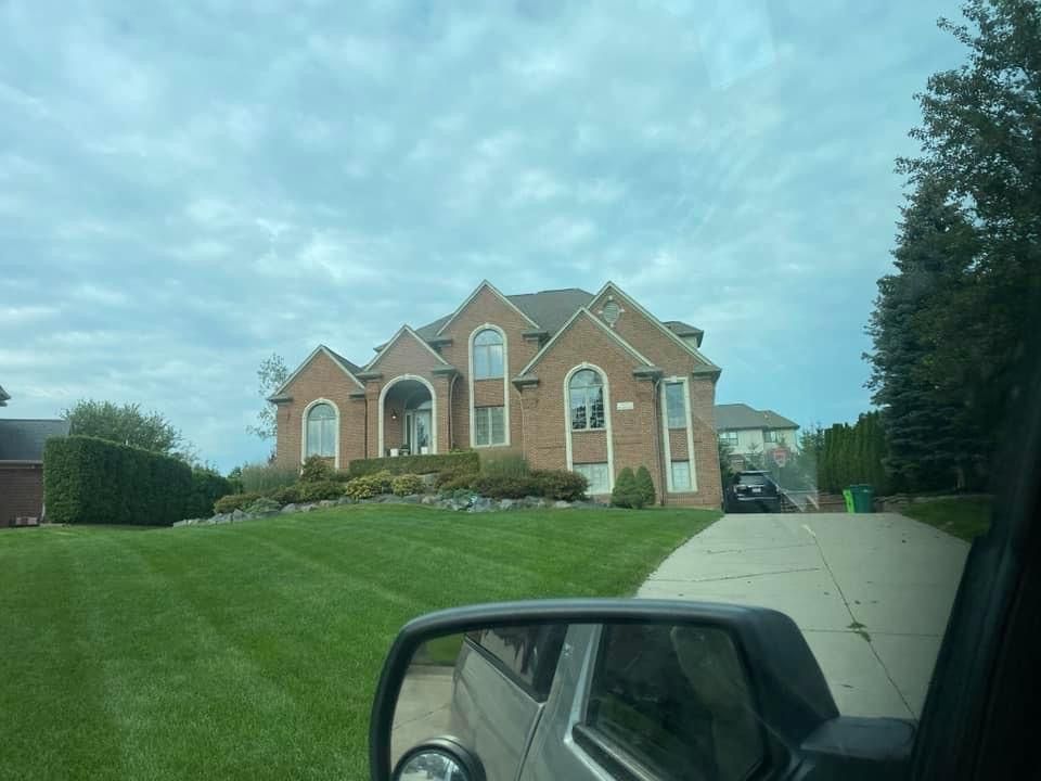 A large brick house is sitting on top of a lush green hill.