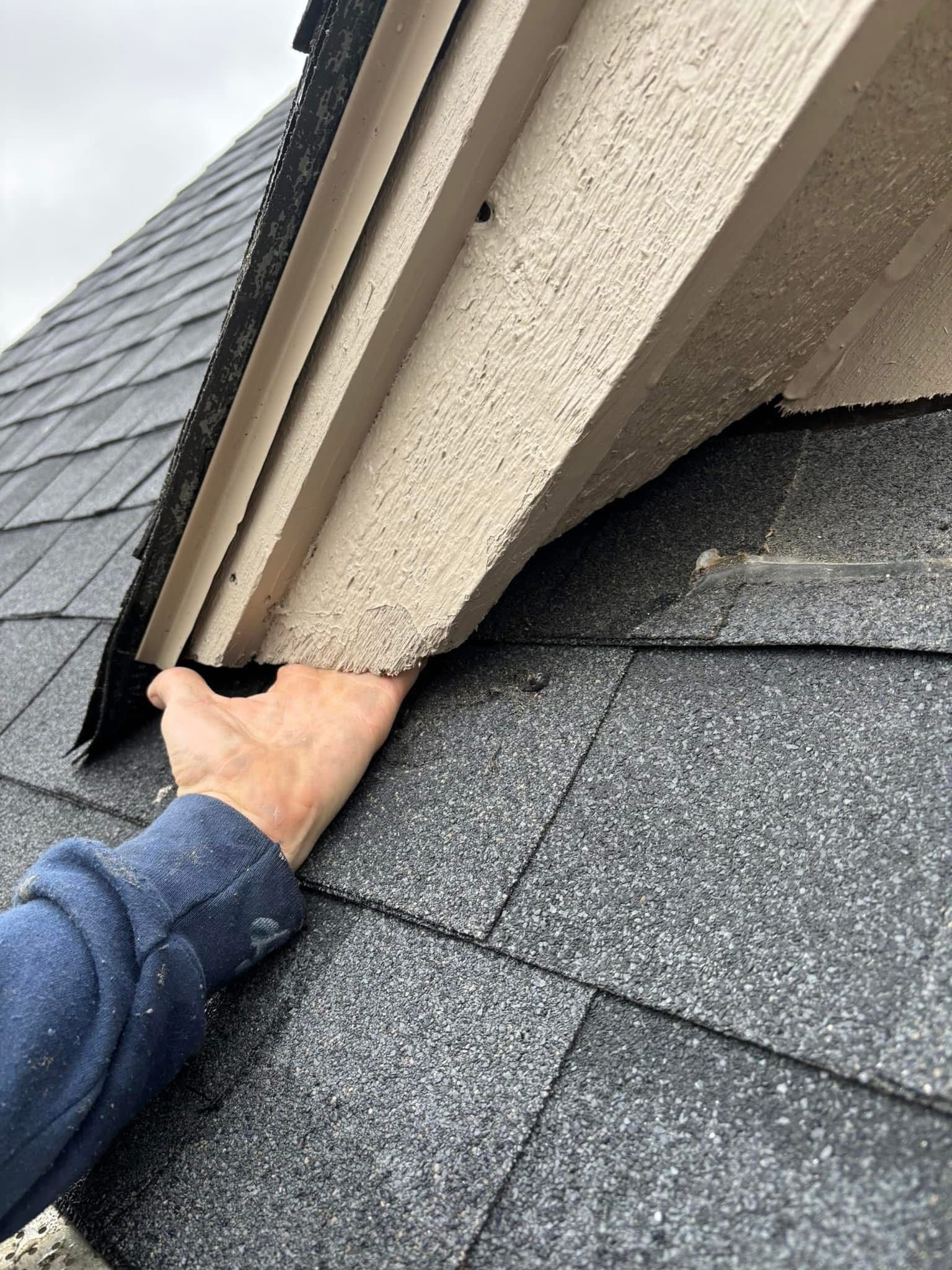 A person is holding a piece of wood on top of a roof.