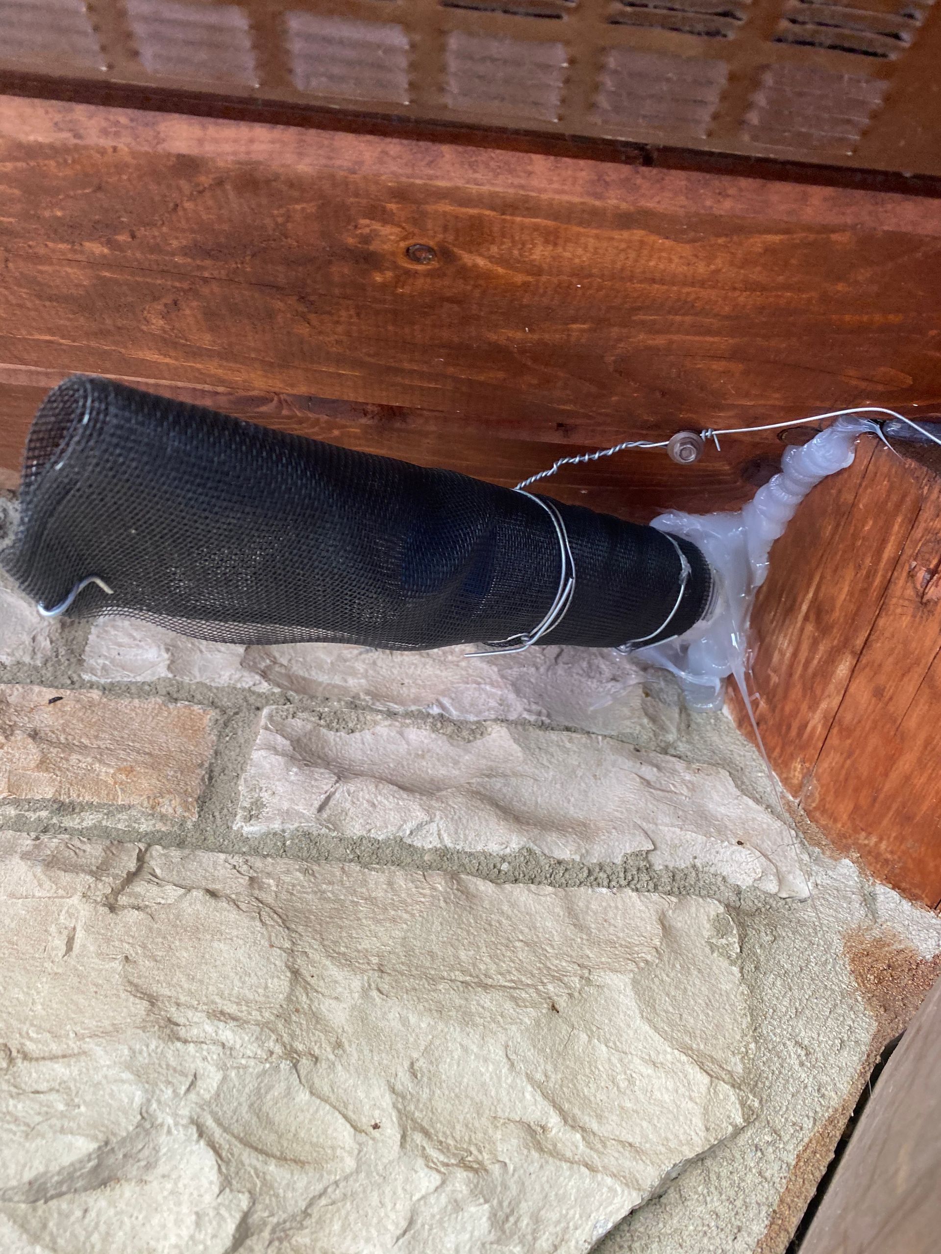 A black bottle is sitting on top of a brick wall.