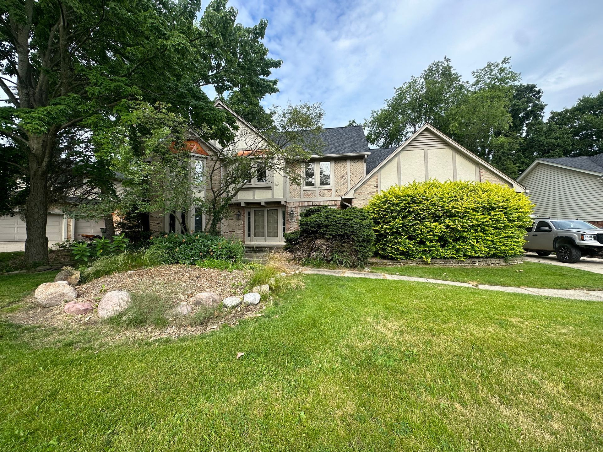 A large house with a lot of grass and trees in front of it.