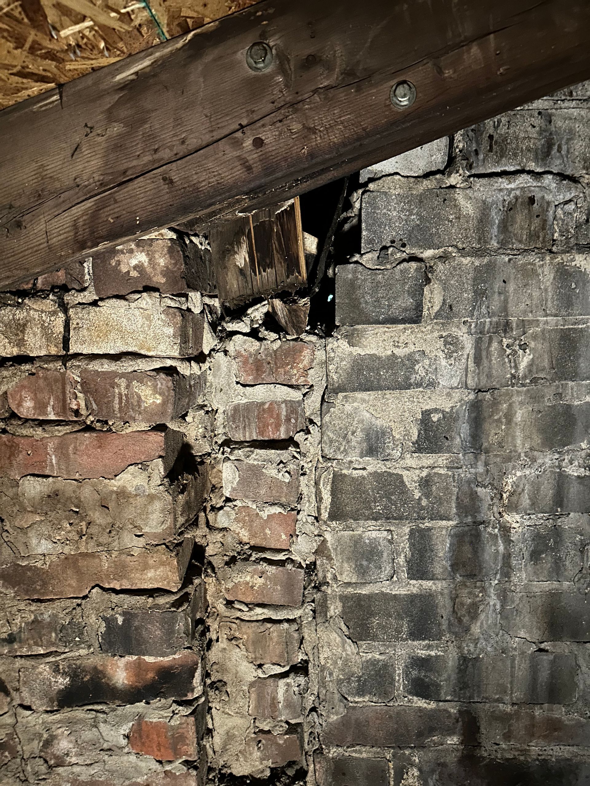 A close up of a brick wall with a metal beam.