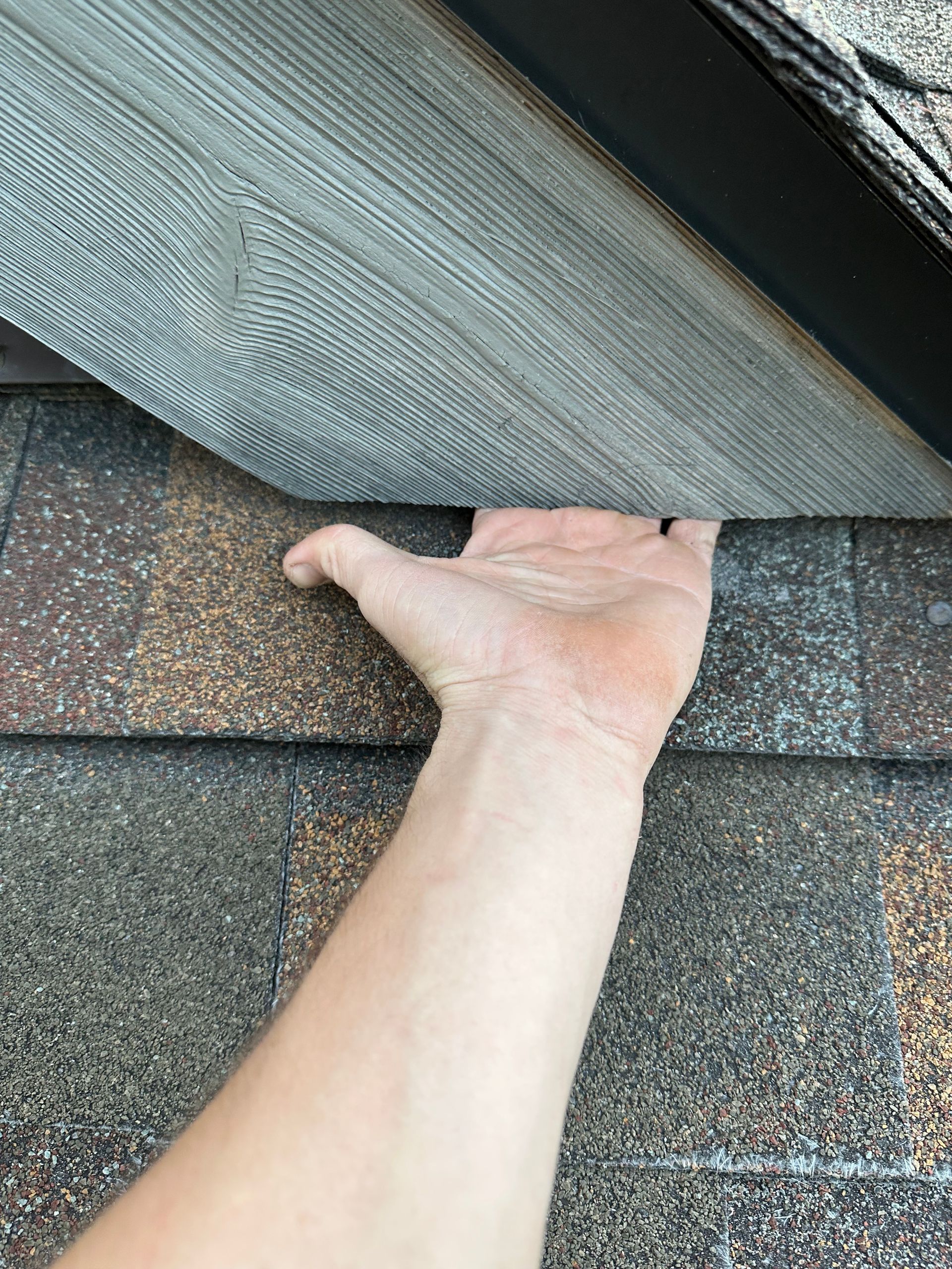 A person is holding a piece of shingles in their hand.