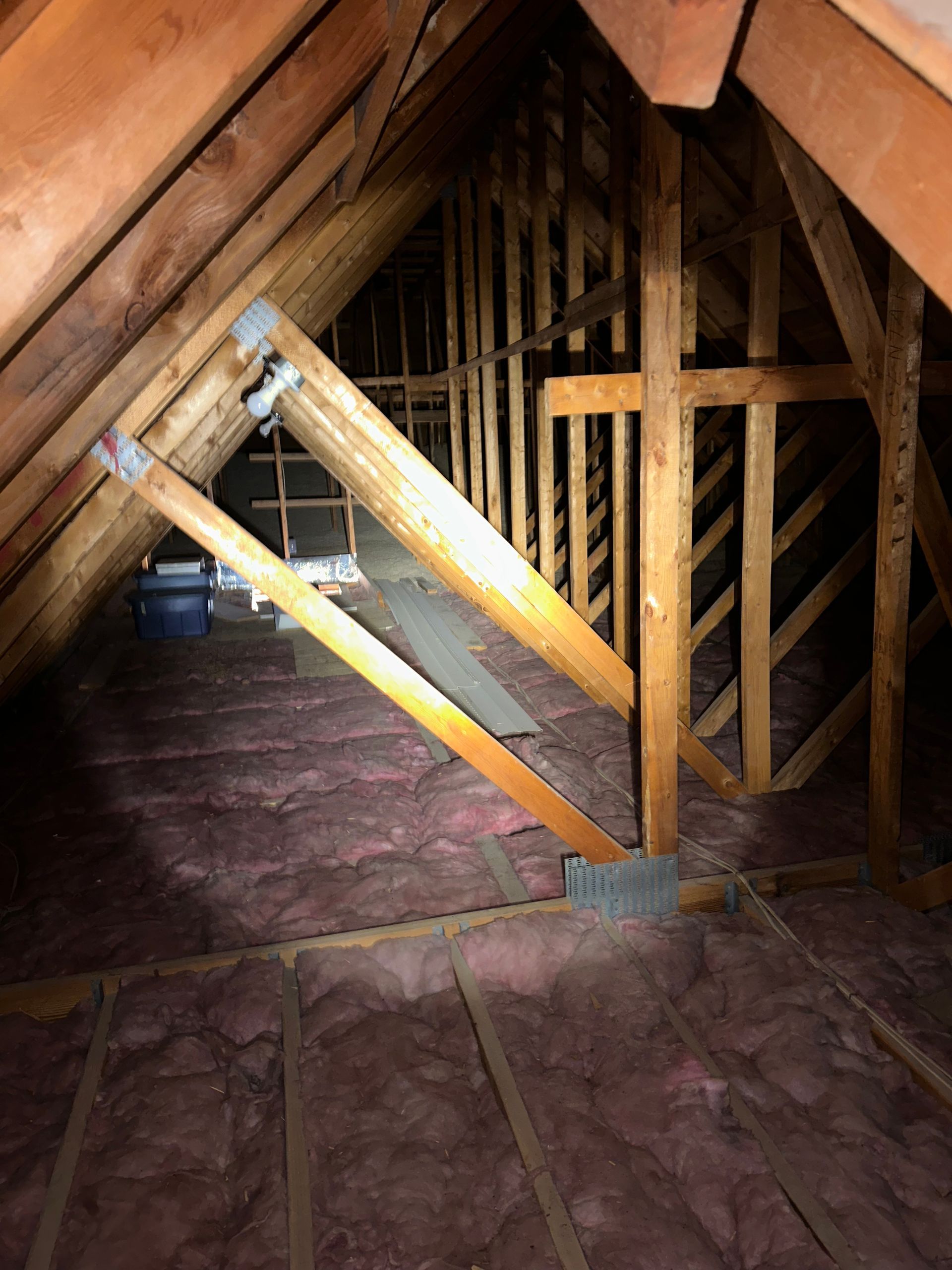 An attic with a lot of wooden beams and insulation