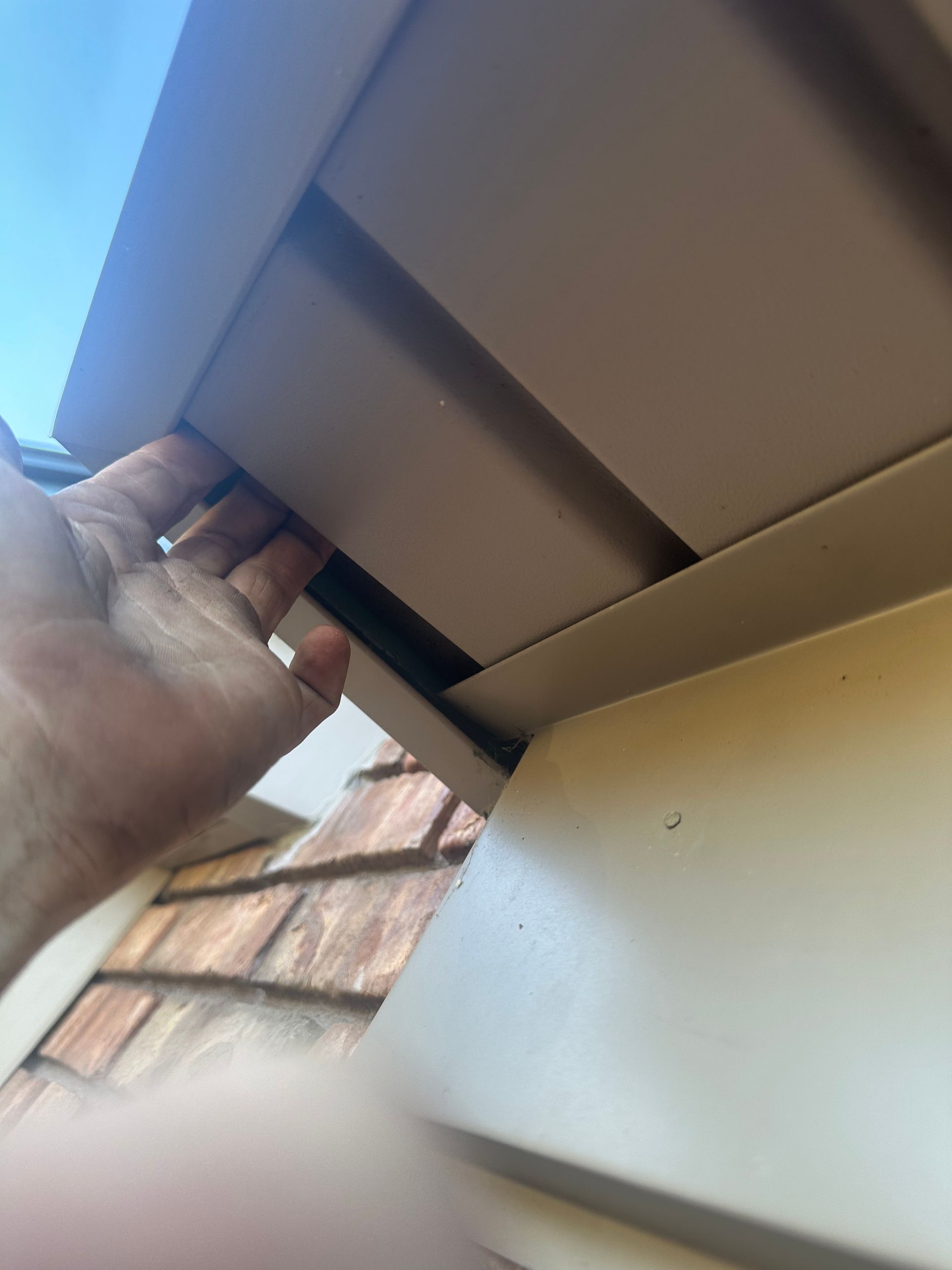 A person is holding a piece of siding on a house.