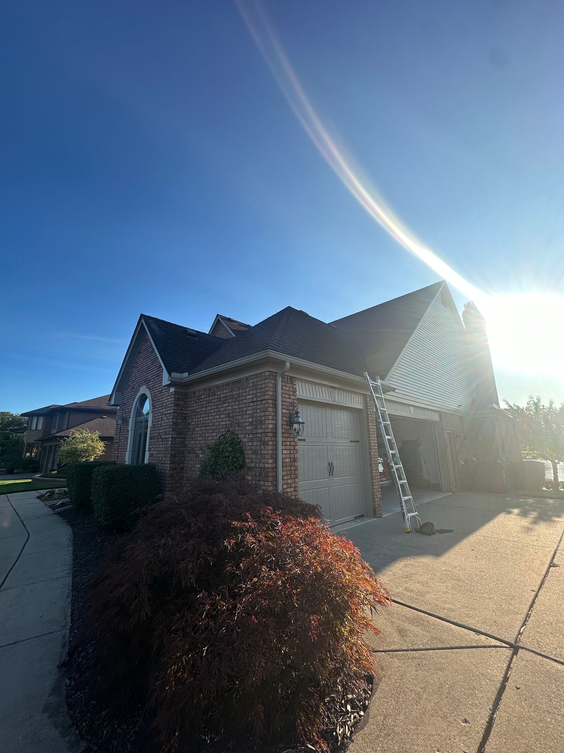A house with a ladder in front of it and a blue sky in the background.