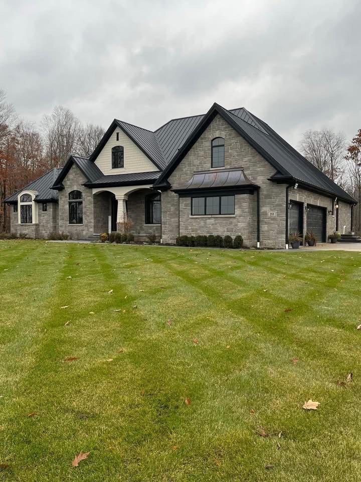 A large house with a black roof is sitting on top of a lush green lawn.