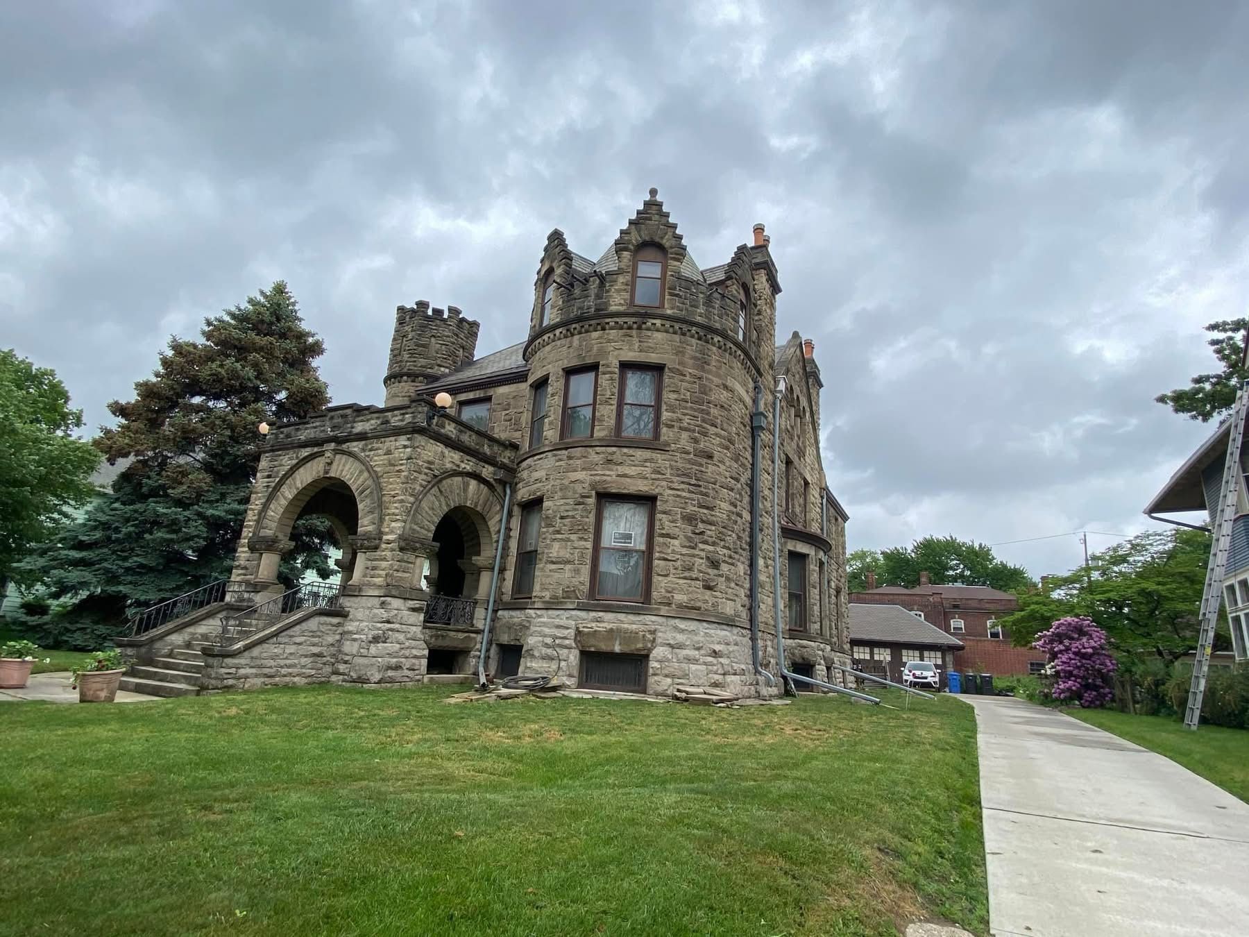A large stone castle sitting on top of a lush green hillside.