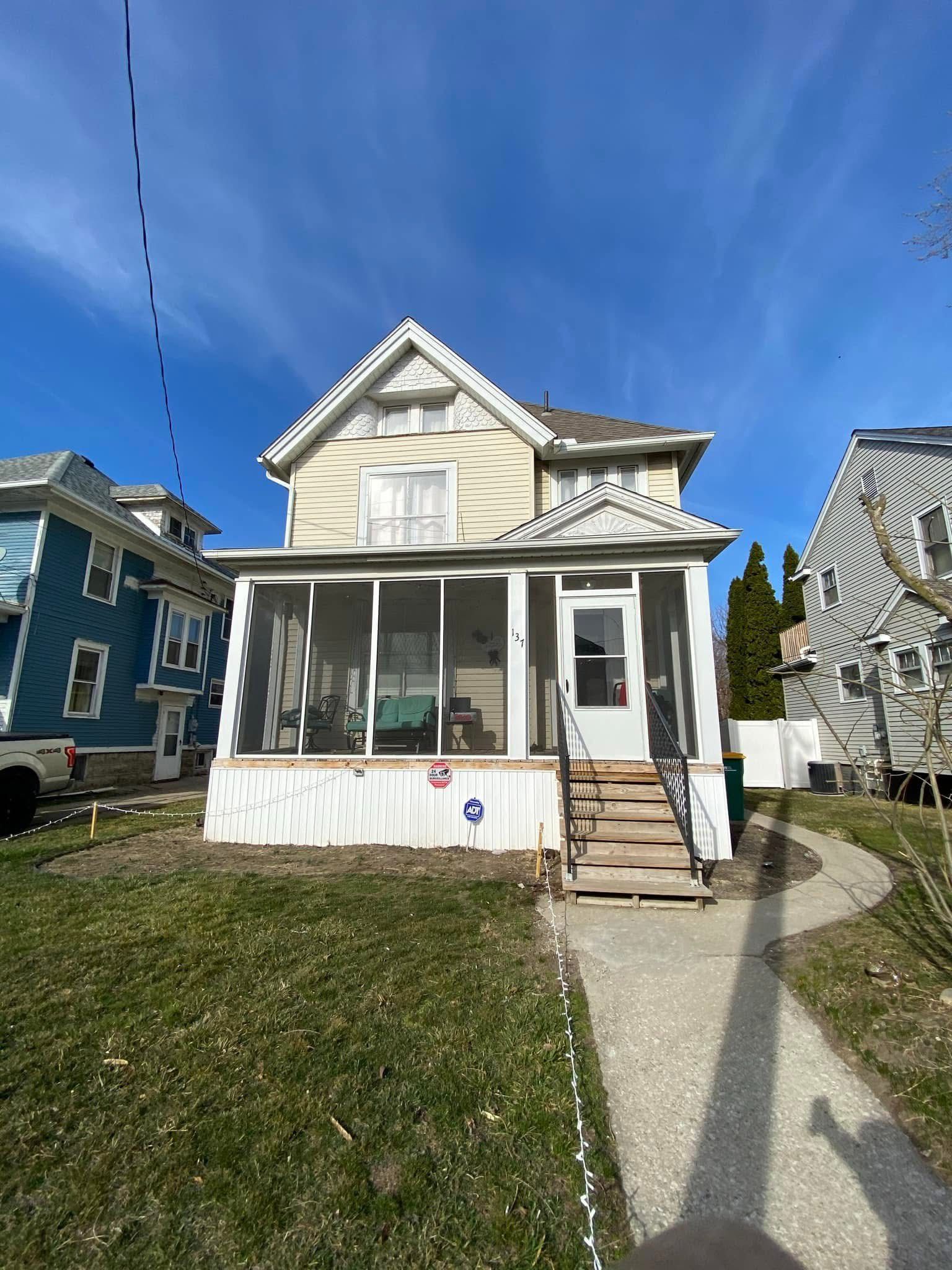 A house with a porch and stairs in front of it.