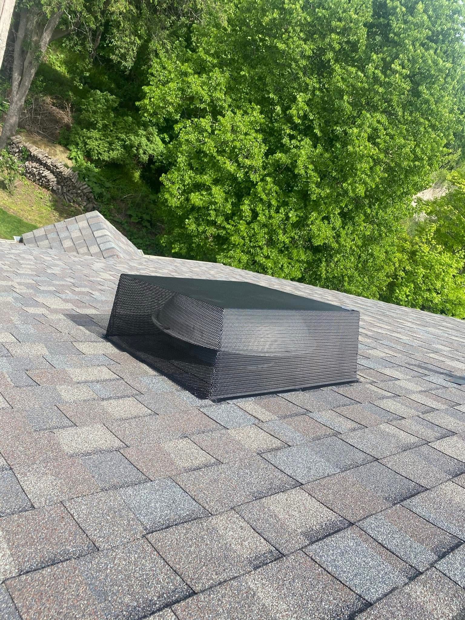 A book is sitting on top of a roof with trees in the background.