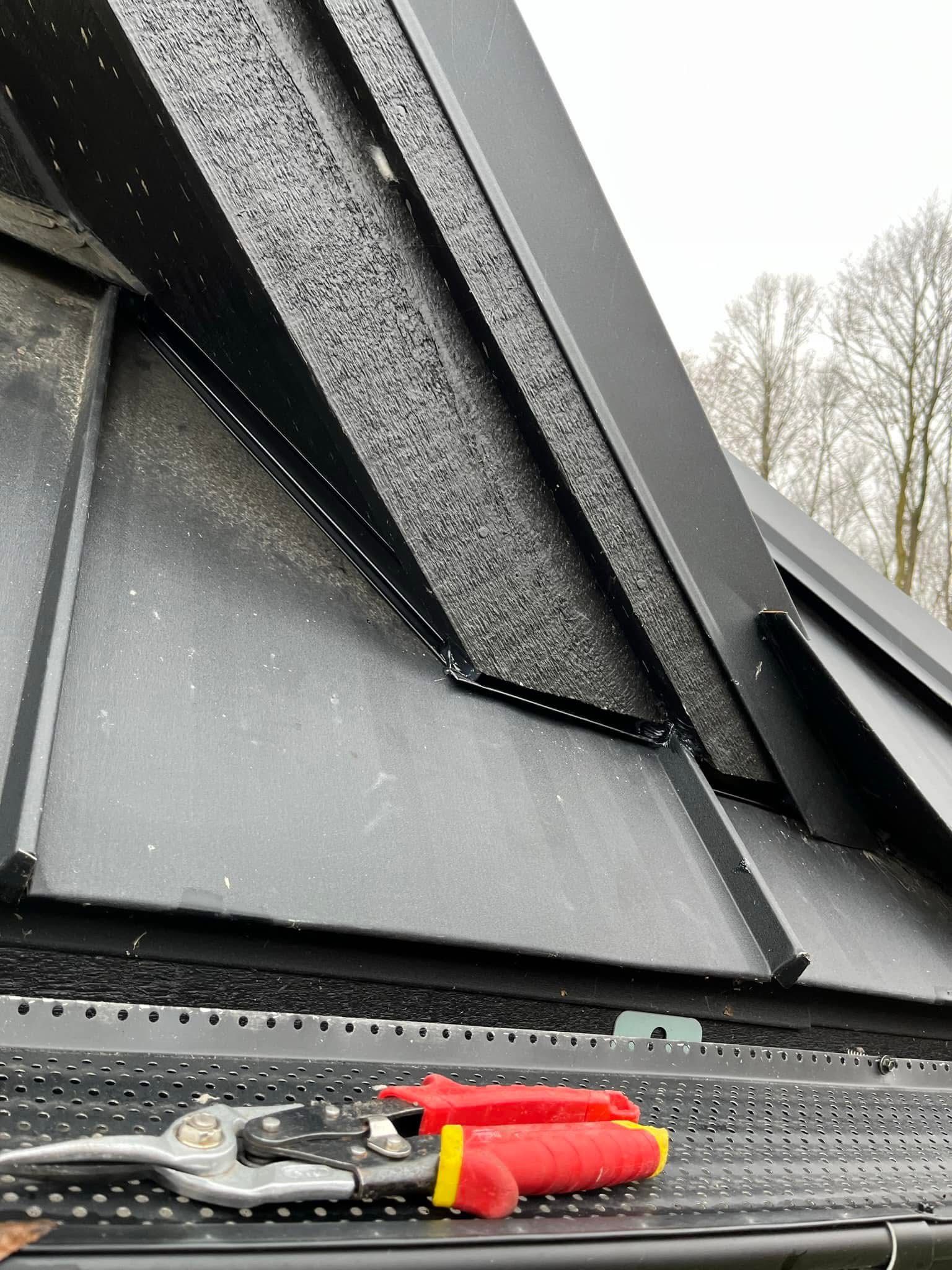 A pair of scissors is sitting on a gutter next to a roof.