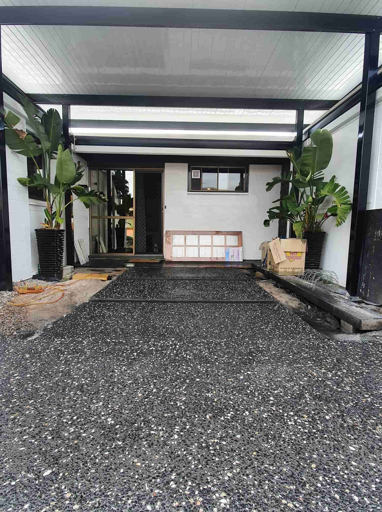 A Black And White House With A Gravel Driveway Leading To It — C & A Concreting In Craignish, QLD