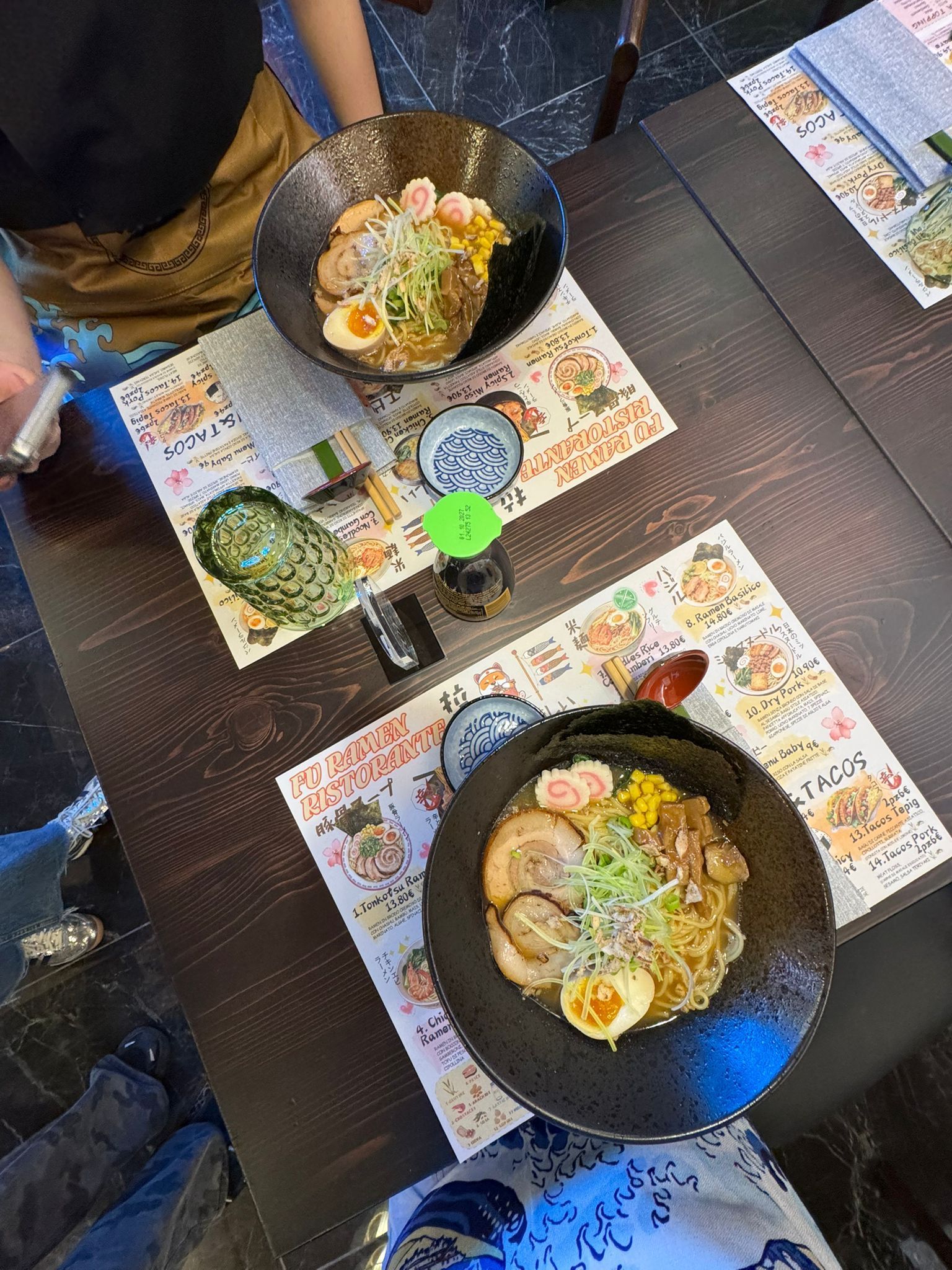 Vista dall'alto di due ciotole di ramen su un tavolo con tovagliette e posate.