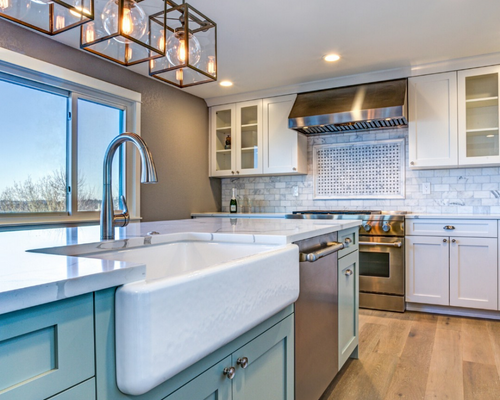 Bright modern kitchen with white cabinets, blue island, farmhouse sink, and stainless steel appliances