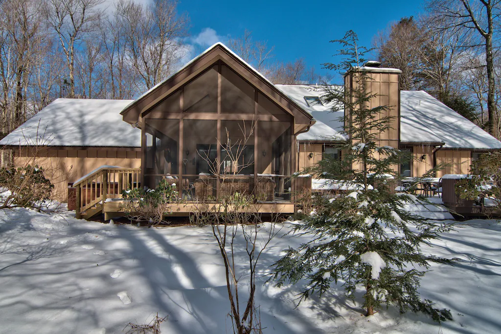 A house with a screened in porch is covered in snow.