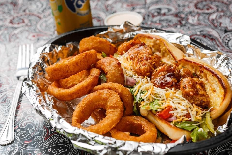 A plate of food with onion rings and a soda on a table.