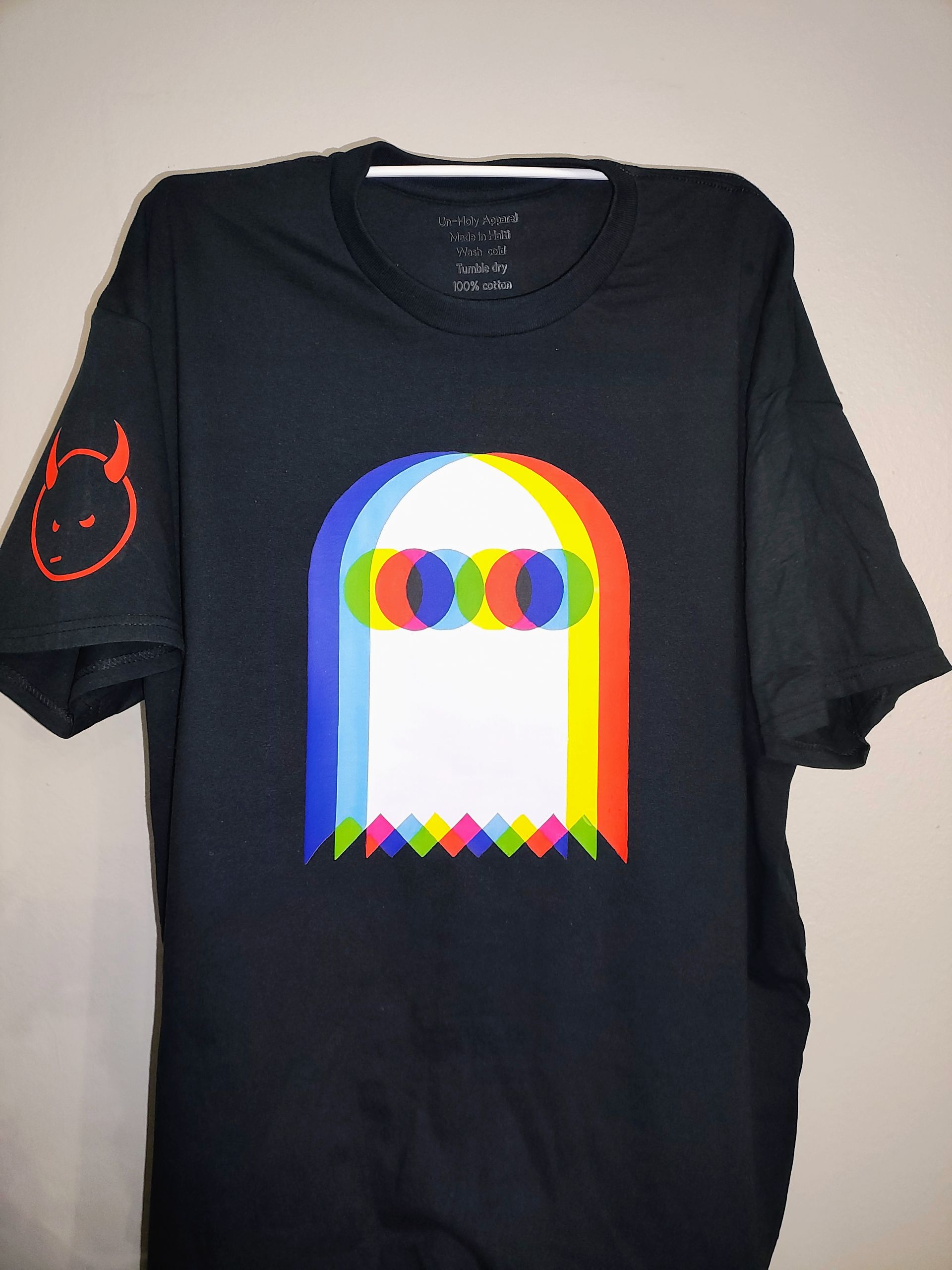 Black t-shirt with pixelated ghost design in red, blue, yellow. A devil face on the left sleeve.