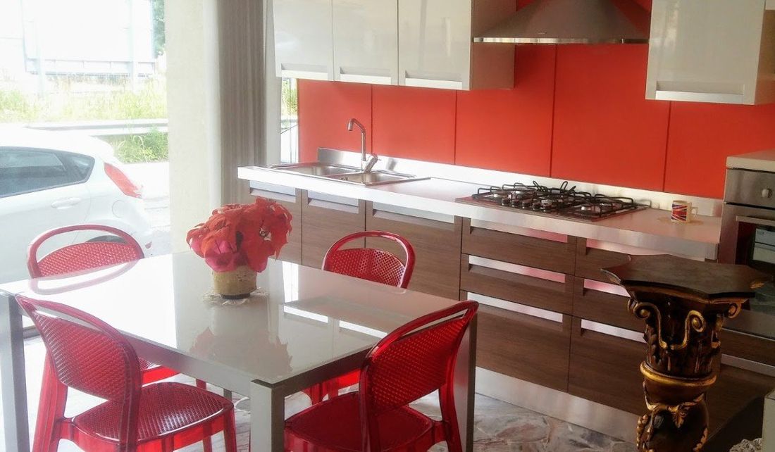 cucina con sedie e paraschizzi rossi
