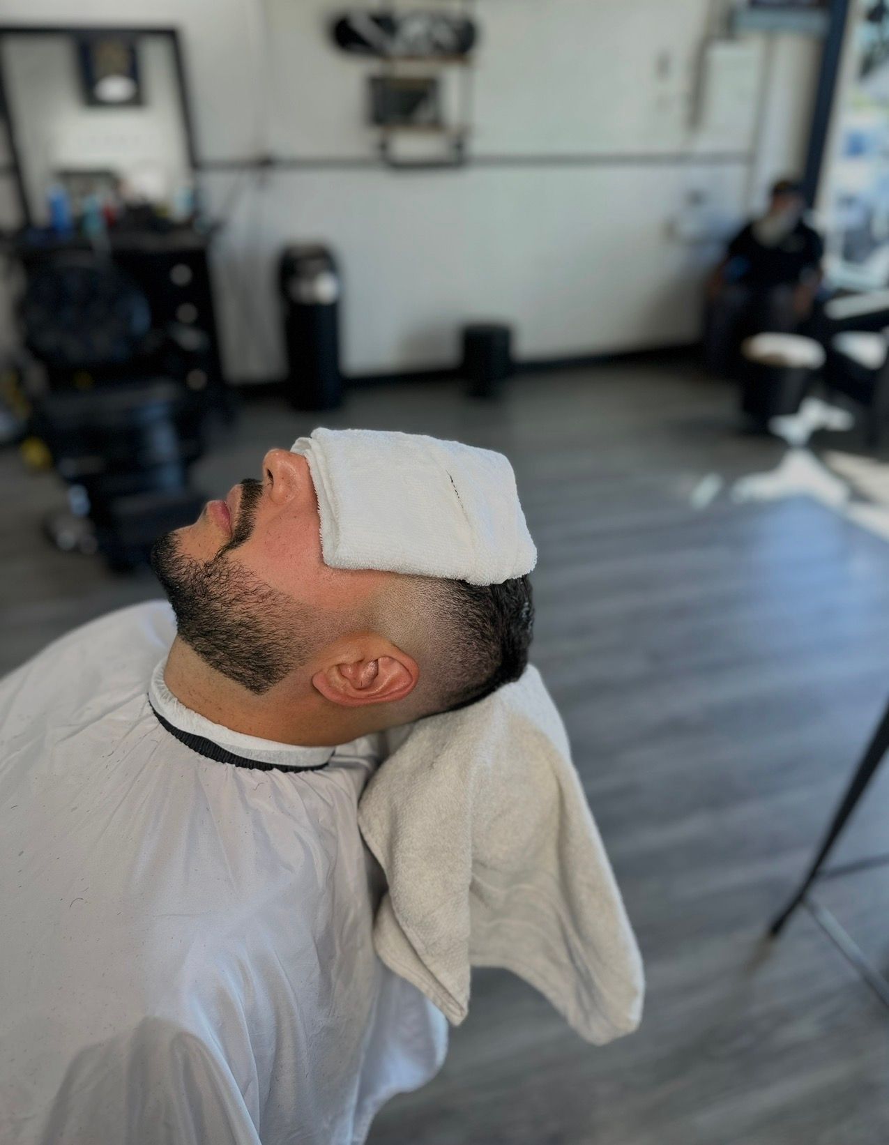 Man in barber chair with a warm towel over his eyes. Barber shop interior.