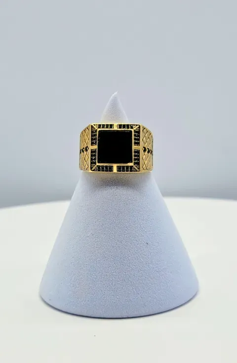 Gold ring with black square stone displayed on a light gray stand.