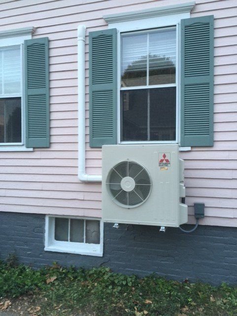 A mitsubishi air conditioner is mounted on the side of a house
