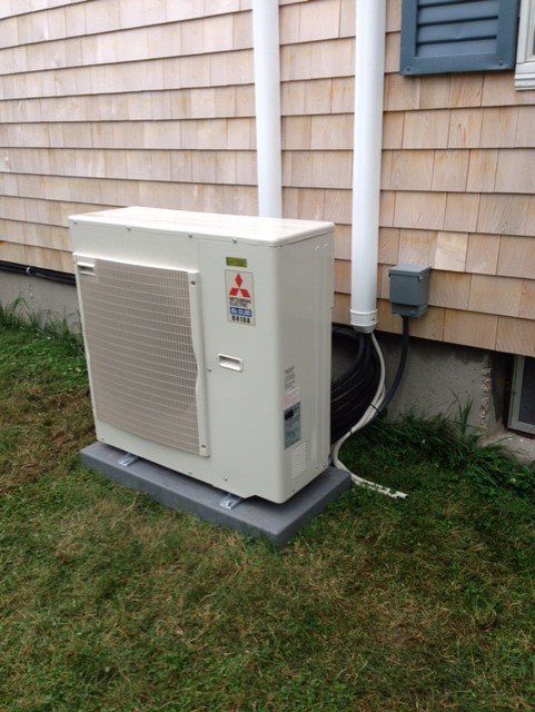 A mitsubishi air conditioner is sitting outside of a house