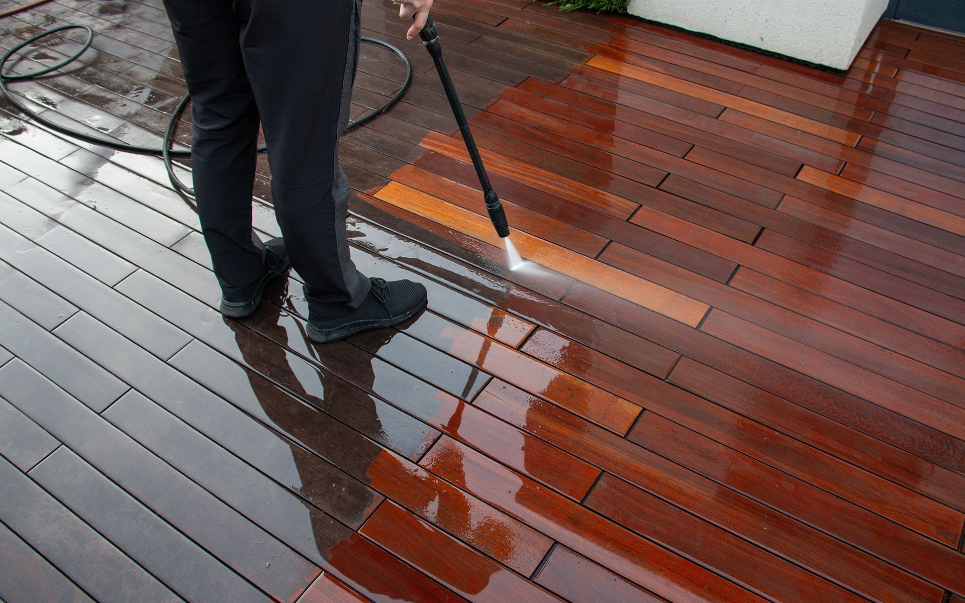 Person power washing a wooden deck.