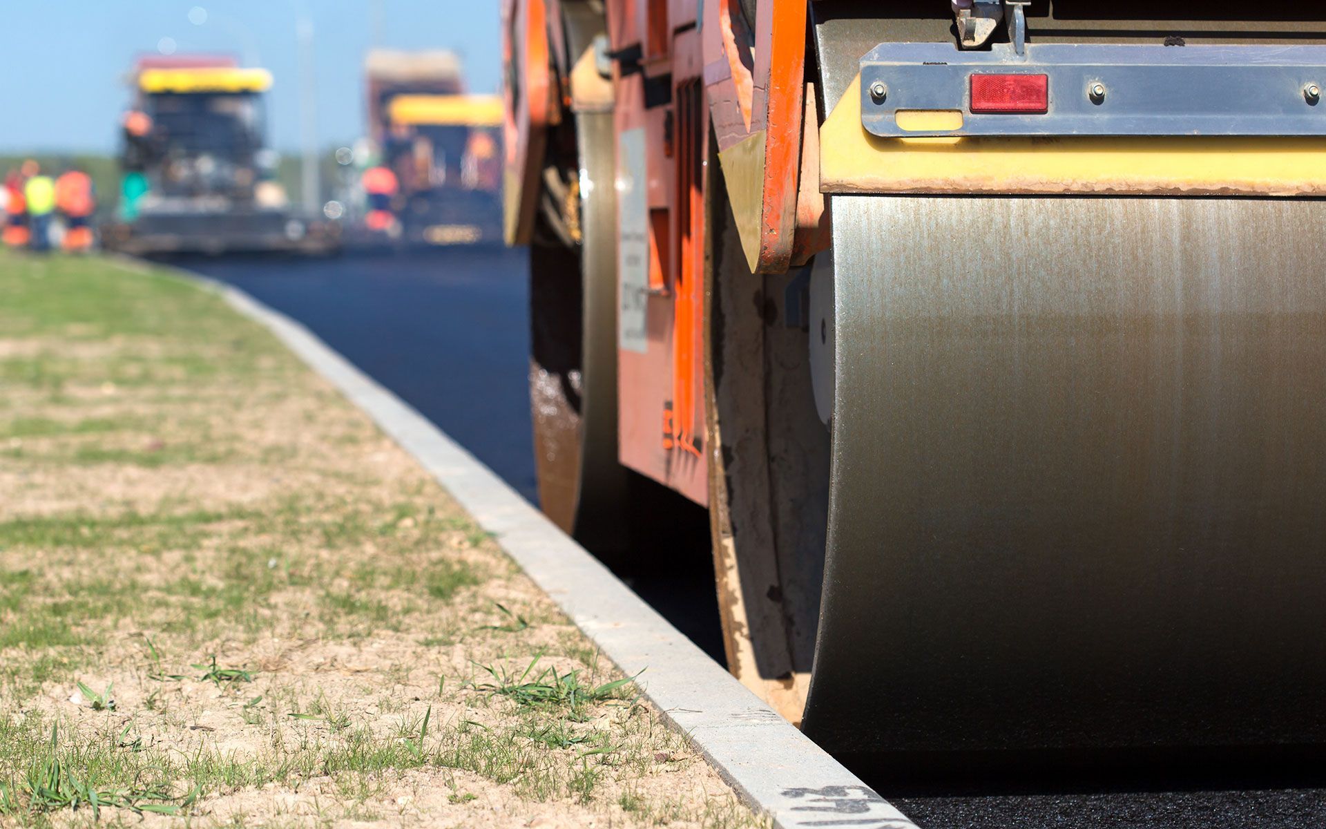 Road roller compacting fresh asphalt on a highway, construction scene.