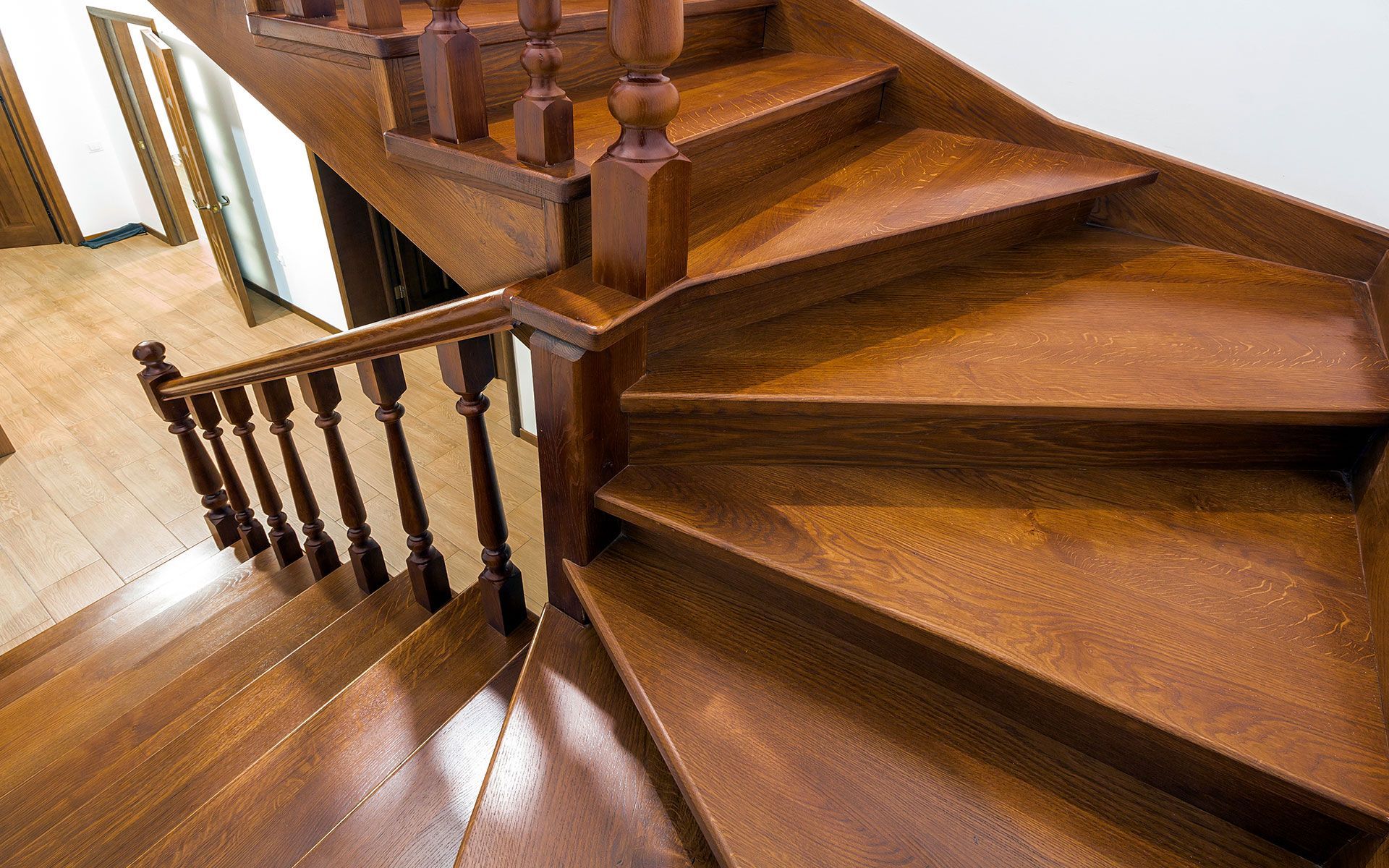 Wooden curved staircase with detailed railing, leading upwards.