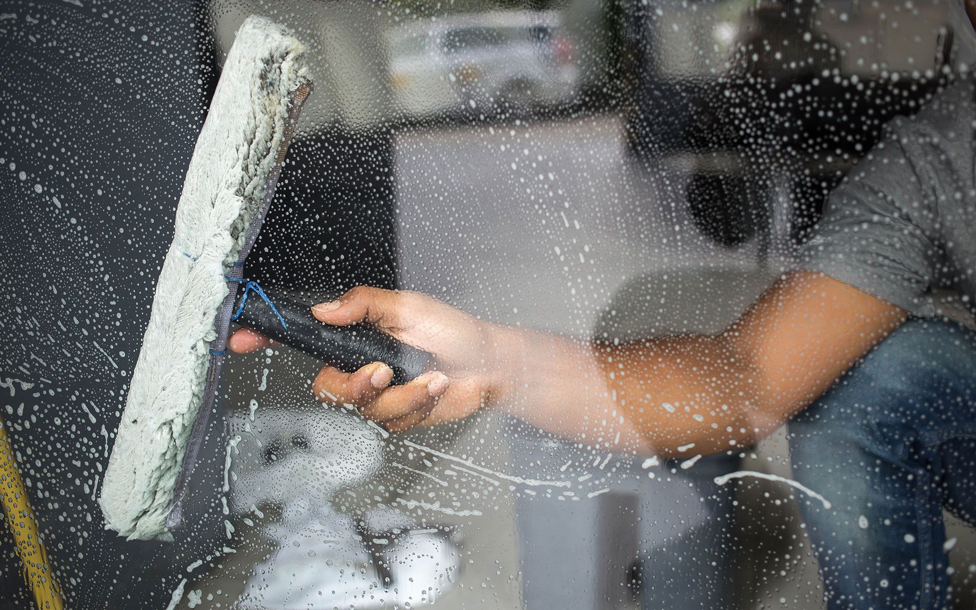 Person cleaning a window with a squeegee, outdoors.