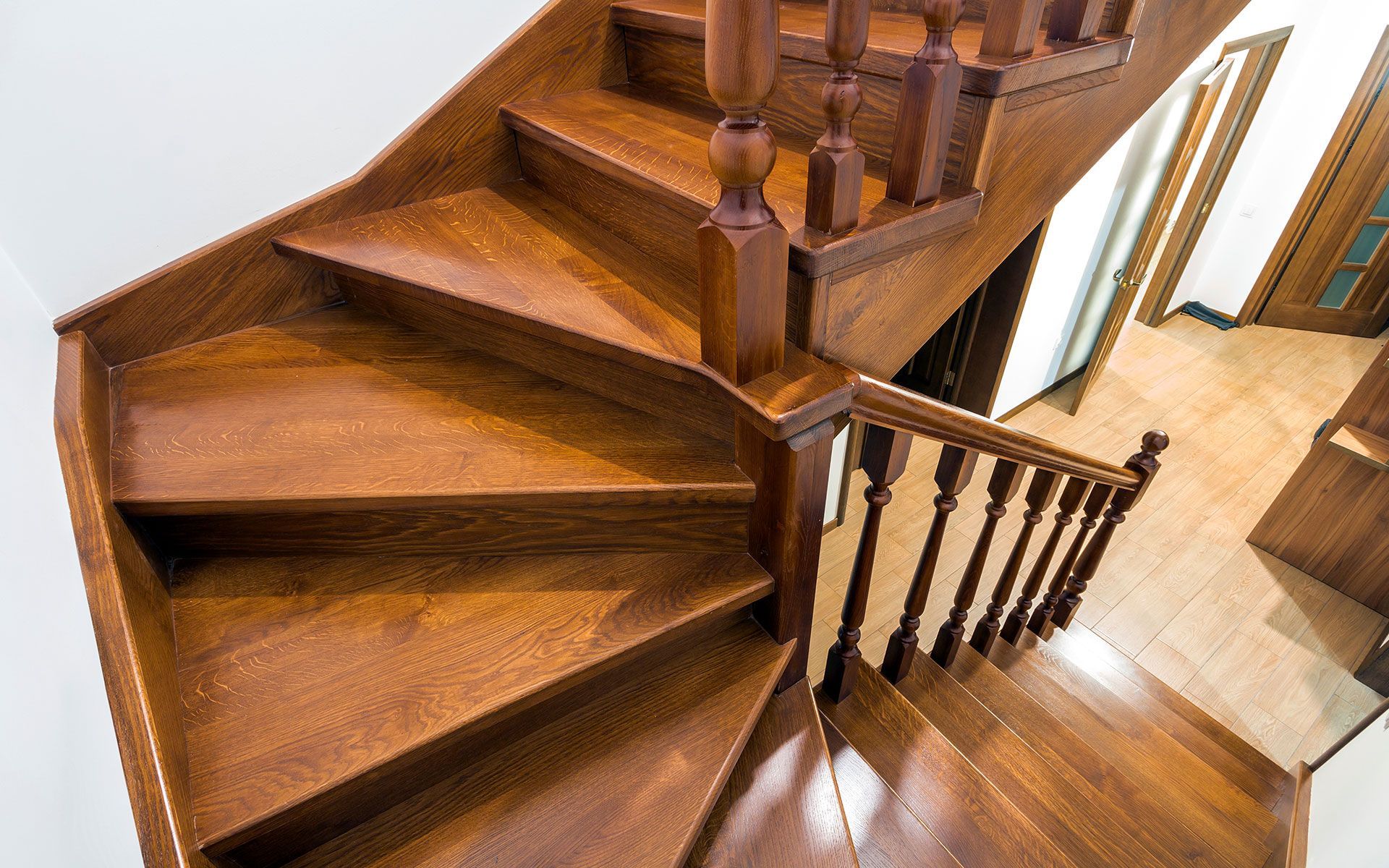 Wooden staircase with brown railing and steps; viewed from above.
