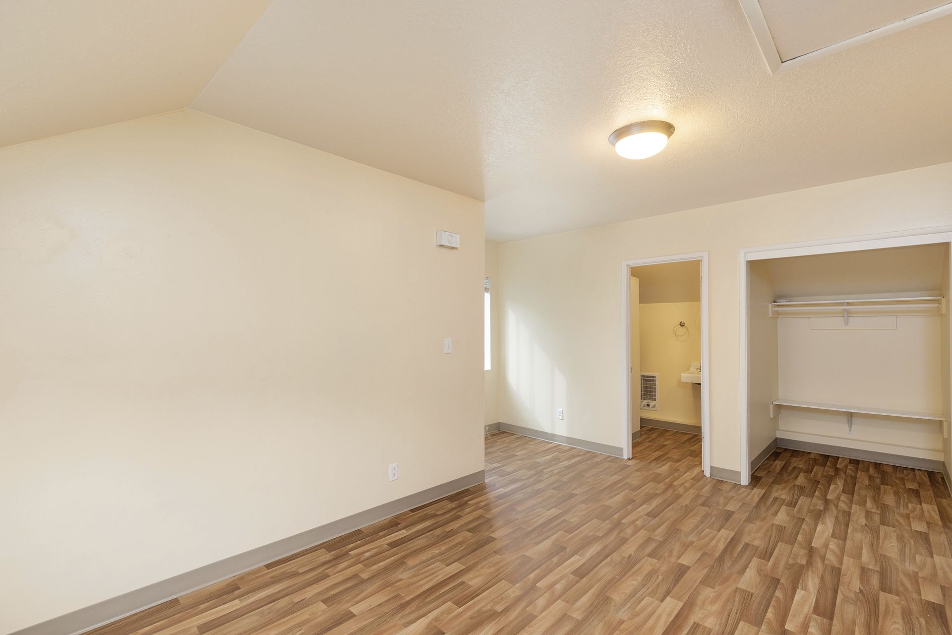An empty room with hardwood floors and a closet.